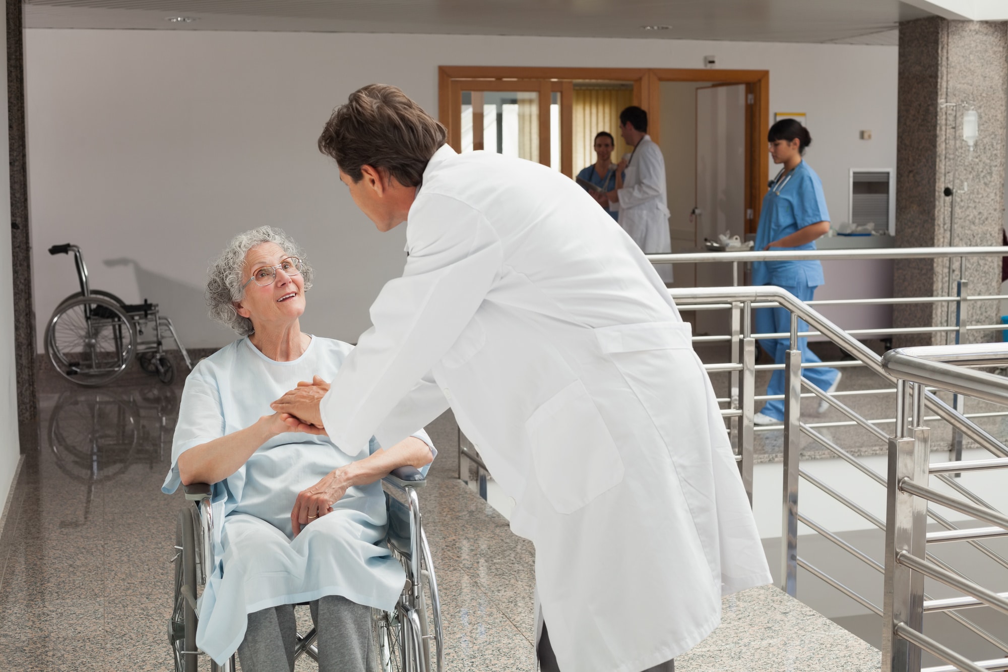 elderly woman sitting on a wheelchair in a hospital while talking with doctor