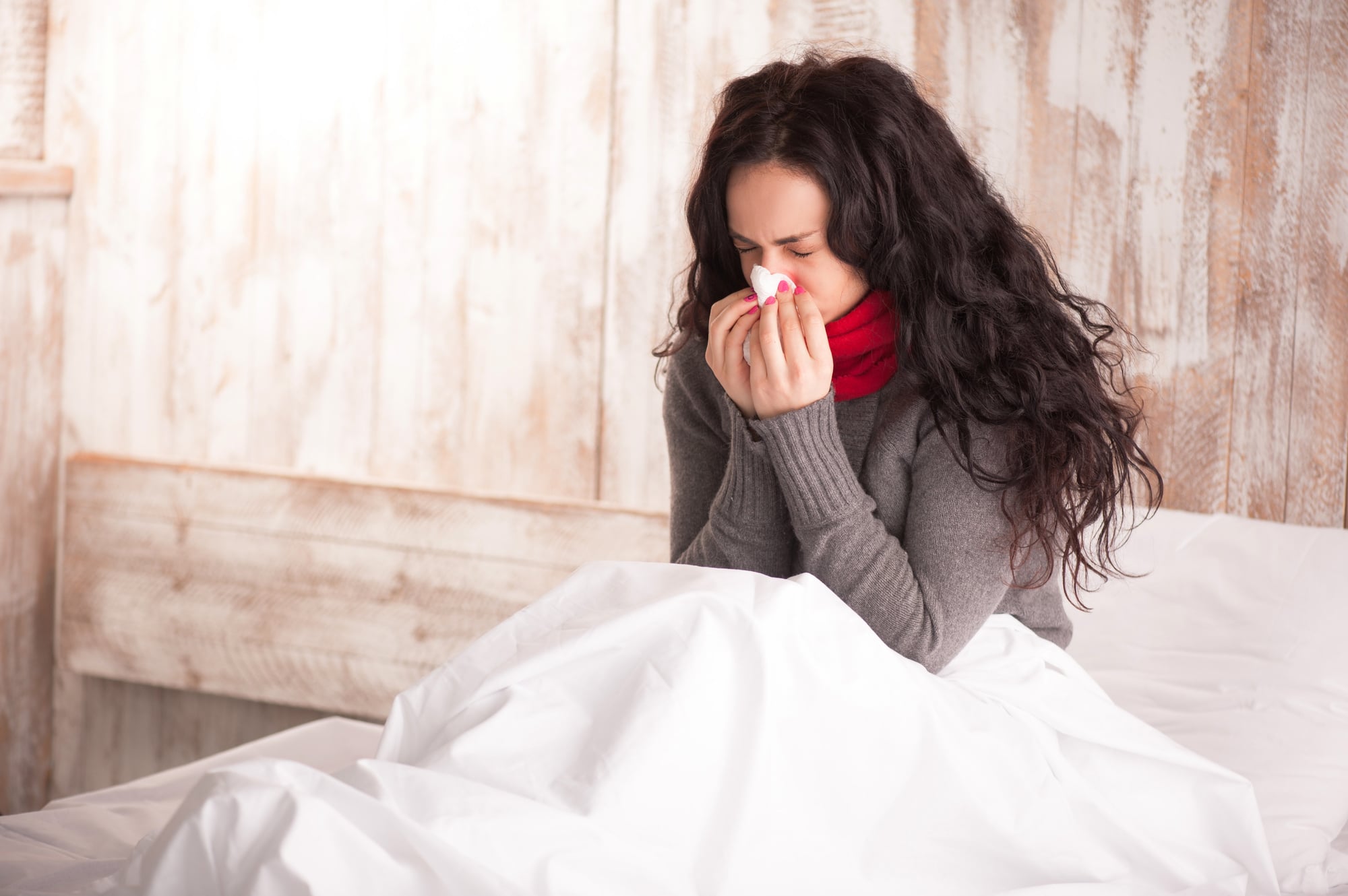 woman blowing nose while in bed