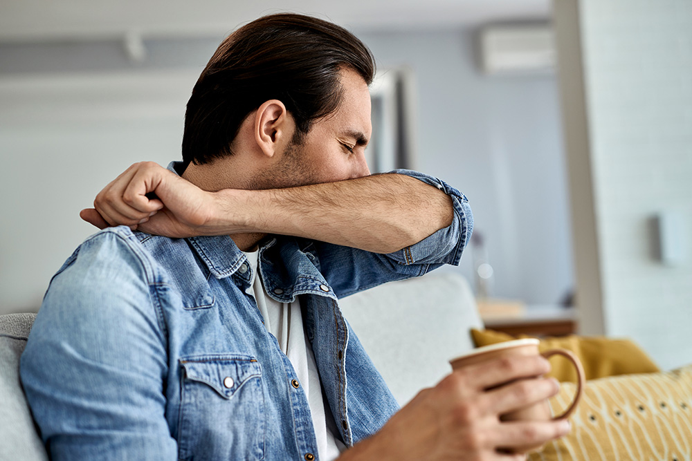 Person coughing into their elbow, a common symptom of bronchitis
